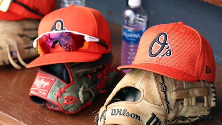 Mar 11, 2024; Tampa, Florida, USA;  A detailed view of Baltimore Orioles baseball hats and gloves in the dugout during the first inning against the New York Yankees at George M. Steinbrenner Field.