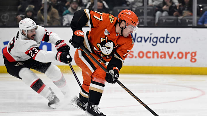 Dec 1, 2024; Anaheim, California, USA;  Anaheim Ducks right wing Frank Vatrano (77) controls the puck with pressure from Ottawa Senators defenseman Travis Hamonic (23) during the second period at Honda Center. Mandatory Credit: Alex Gallardo-Imagn Images