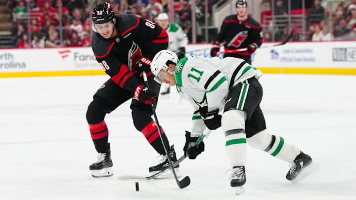 Nov 25, 2024; Raleigh, North Carolina, USA;  Dallas Stars center Logan Stankoven (11) and Carolina Hurricanes center Martin Necas (88) battle over the puck during the second period at Lenovo Center. Mandatory Credit: James Guillory-Imagn Images
