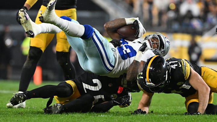 Oct 6, 2024; Pittsburgh, Pennsylvania, USA; Pittsburgh Steelers defenders Payton Wilson (41) and DeShon Elliott (25) upend Dallas Cowboys running back Rico Dowdle (23) during the second quarter at Acrisure Stadium. Mandatory Credit: Barry Reeger-Imagn Images





