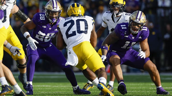 Huskies linebackers Khmori House (28) and Alphonzo Tuputala (11) tackle Michigan Wolverines running back Kalel Mullings in the first quarter.