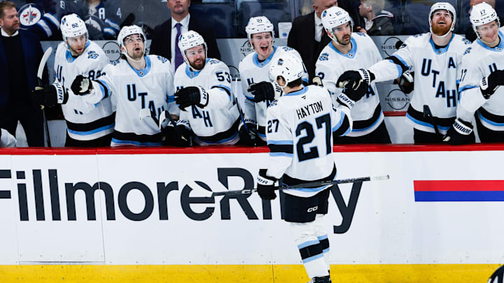 Jan 24, 2025; Winnipeg, Manitoba, CAN; Utah Hockey Club forward Barrett Hayton (27) is congratulated by his teammates on his goal against Winnipeg Jets goalie Connor Hellebuyck (not pictured) during the third period at Canada Life Centre. Mandatory Credit: Terrence Lee-Imagn Images