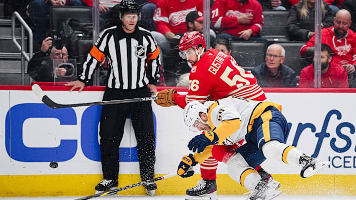 Nov 26, 2025; Detroit, Michigan, USA; Detroit Red Wings defenseman Erik Gustafsson (56) and Nashville Predators left wing Michael Bunting (58) battle for the puck during the first period at Little Caesars Arena.
