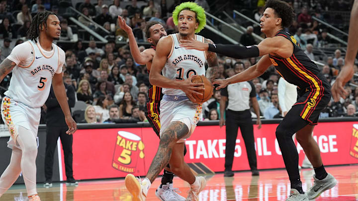 Dec 19, 2024; San Antonio, Texas, USA;  San Antonio Spurs forward Jeremy Sochan (10) drives in between Atlanta Hawks guard Trae Young (11) and forward Jalen Johnson (1) in the first half at Frost Bank Center. Mandatory Credit: Daniel Dunn-Imagn Images