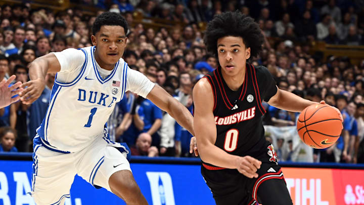 Jan 26, 2026; Durham, North Carolina, USA; Louisville Cardinals guard Mikel Brown Jr. (0) drives to the basket as Duke Blue Devils guard Caleb Foster (1) defends during the first half at Cameron Indoor Stadium. Mandatory Credit: Rob Kinnan-Imagn Images