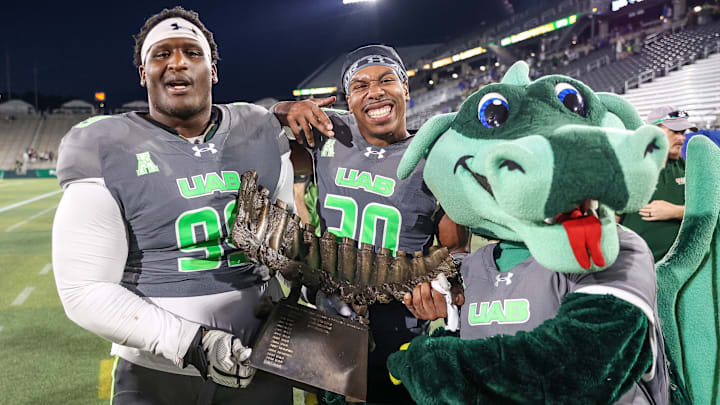 Eamon Smalls #99 and AJ Brown #20 of the UAB Blazers pose with the Battle of the Bones trophy after winning the game against the Memphis Tigers at Protective Stadium on October 18, 2025 in Birmingham, Alabama.
