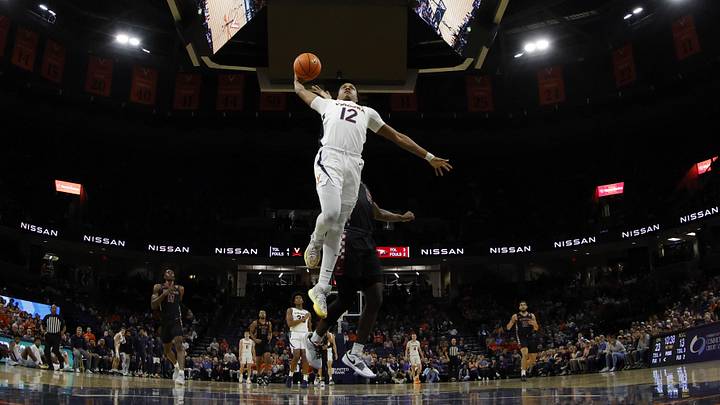 Dec 5, 2023; Charlottesville, Virginia, USA; Virginia Cavaliers guard Elijah Gertrude (12) dunks the ball as North Carolina Central Eagles forward Timmy Adedire (5) defends in the first half at John Paul Jones Arena. Mandatory Credit: Geoff Burke-Imagn Images