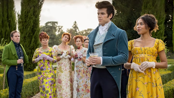 (L to R) BEN MILLER as LORD FEATHERINGTON, POLLY WALKER as PORTIA FEATHERINGTON, BESSIE CARTER as PRUDENCE FEATHERINGTON, HARRIET CAINS as PHILLIPA FEATHERINGTON, LUKE NEWTON as COLIN BRIDGERTON and RUBY BARKER as MARINA THOMPSON in episode 106 of BRIDGERTON 