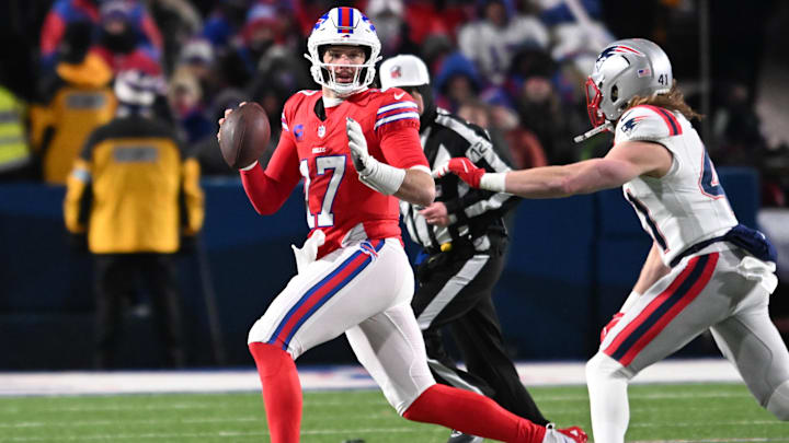 Buffalo Bills quarterback Josh Allen looks downfield to throw while avoiding New England Patriots safety Brenden Schooler.