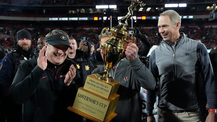 Georgia Governor Brian Kemp hand Georgia coach Kirby Smart the governor cup after Georgia won a NCAA college football game against Georgia Tech in overtime in Athens, Ga., on Friday, Nov. 29, 2024. Georgia won 44-42.