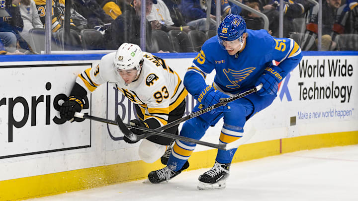 Dec 9, 2025; St. Louis, Missouri, USA; Boston Bruins center Fraser Minten (93) and St. Louis Blues defenseman Colton Parayko (55) battle for the puck during the third period at Enterprise Center. Mandatory Credit: Jeff Curry-Imagn Images