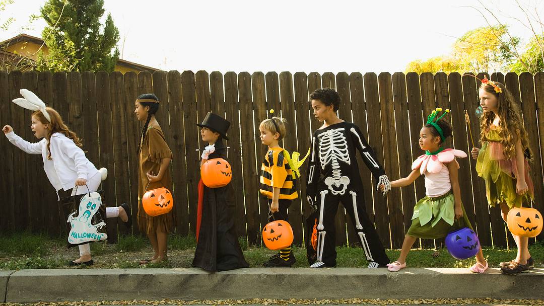 Niños con disfraces de Halloween cogidos de la mano | Jupiterimages/GettyImages