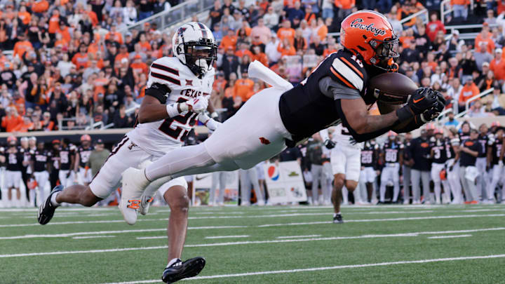 Oklahoma State's Rashod Owens catches a pass while Texas Tech's Chapman Lewis looks on during an NCAA football game on Saturday, Nov. 23, 2024, in Stillwater, Okla.