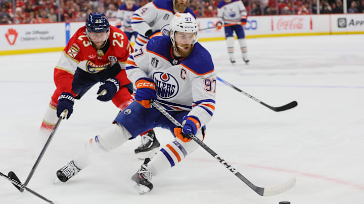 Jun 24, 2024; Sunrise, Florida, USA; Edmonton Oilers forward Connor McDavid (97) controls the puck as Florida Panthers forward Carter Verhaeghe (23) reaches to defend during the first period in game seven of the 2024 Stanley Cup Final at Amerant Bank Arena. Mandatory Credit: Sam Navarro-Imagn Images