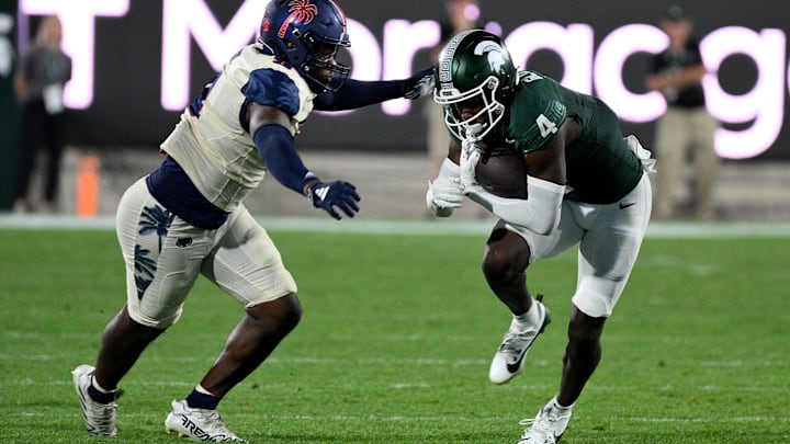 Aug 30, 2024; East Lansing, Michigan, USA;  Michigan State Spartans wide receiver Jaron Glover (4) runs from Florida Atlantic Owls cornerback Logic Hudgens (8) in the third quarter at Spartan Stadium. Mandatory Credit: Dale Young-Imagn Images