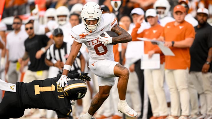 Oct 26, 2024; Nashville, Tennessee, USA; Texas Longhorns wide receiver DeAndre Moore Jr. (0) stiff arms Vanderbilt Commodores safety CJ Taylor (1) as he crosses the goal line  during the first half at FirstBank Stadium. Mandatory Credit: Steve Roberts-Imagn Images