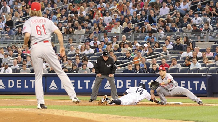 May 18, 2012; Bronx, NY, USA;   New York Yankees center fielder Curtis Granderson (14) slides back to first as Cincinnati Reds first baseman Joey Votto (19) waits for the ball from starting pitcher Bronson Arroyo (61) during the fourth inning at Yankee Stadium.  Mandatory Credit: Anthony Gruppuso-Imagn Images