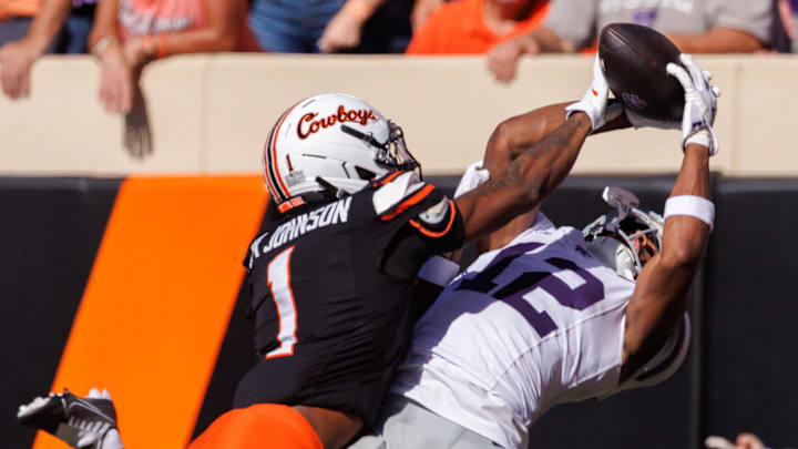 Nov 15, 2025; Stillwater, Oklahoma, USA; Kansas State Wildcats wide receiver Jaron Tibbs (12) attempts a reception around Oklahoma State Cowboys cornerback Jk Johnson (1) during the first half at Boone Pickens Stadium. Mandatory Credit: William Purnell-Imagn Images