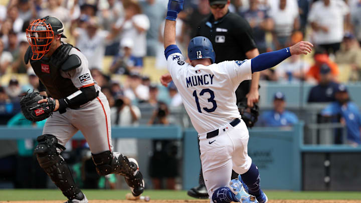Sep 21, 2025; Los Angeles, California, USA;  Los Angeles Dodgers third baseman Max Muncy (13) slides home to score a run on an RBI single by left fielder Michael Conforto (not pictured) ahead of a throw to San Francisco Giants catcher Andrew Knizner (21) during the seventh inning at Dodger Stadium. Mandatory Credit: Kiyoshi Mio-Imagn Images