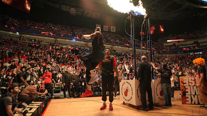 Jan 4, 2025; Miami, Florida, USA;  Miami Heat center Bam Adebayo, left, leaps into the air after warming-up with the help of center Kel'el Ware (7) before the game against the Utah Jazz at Kaseya Center. Mandatory Credit: Jim Rassol-Imagn Images