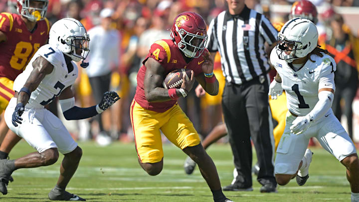 Oct 12, 2024; Los Angeles, California, USA; USC Trojans running back Woody Marks (4) runs the ball for a first down before he is stopped by Penn State Nittany Lions safety Jaylen Reed (1) and cornerback Zion Tracy (7) in the first half at United Airlines Field at the Los Angeles Memorial Coliseum. Mandatory Credit: Jayne Kamin-Oncea-Imagn Images