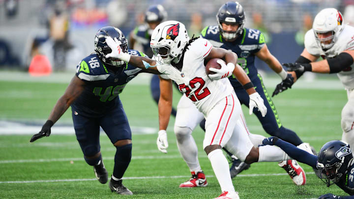 Nov 9, 2025; Seattle, Washington, USA; Arizona Cardinals running back Michael Carter (22) rushes and stiff arms Seattle Seahawks linebacker Tyrice Knight (48) during the fourth quarter at Lumen Field. Mandatory Credit: Steven Bisig-Imagn Images