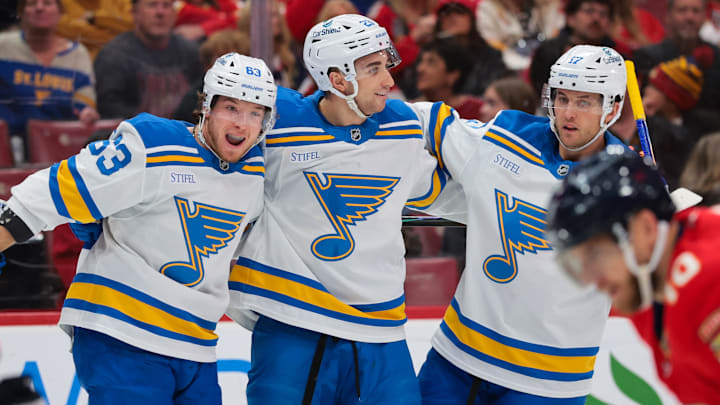 Dec 20, 2025; Sunrise, Florida, USA; St. Louis Blues left wing Jake Neighbours (63) celebrates with defenseman Logan Mailloux (23) and defenseman Cam Fowler (17) after scoring against the Florida Panthers during the first period at Amerant Bank Arena. Mandatory Credit: Sam Navarro-Imagn Images