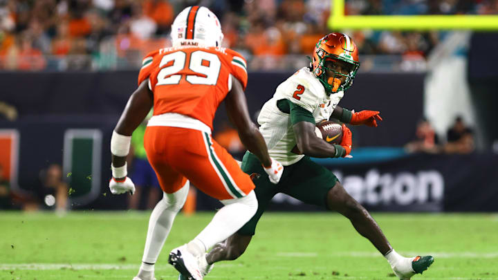 Sep 7, 2024; Miami Gardens, Florida, USA; Florida A&M Rattlers wide receiver Jamari Gassett (2) runs with the football against Miami Hurricanes defensive back OJ Frederique Jr. (29) during the third quarter at Hard Rock Stadium. Mandatory Credit: Sam Navarro-Imagn Images