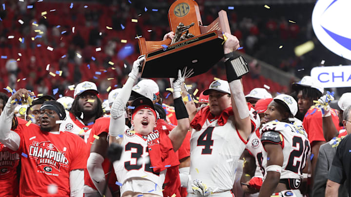 Dec 6, 2025; Atlanta, GA, USA; Georgia Bulldogs running back Cash Jones (32) and Georgia Bulldogs tight end Oscar Delp (4) lift the SEC Championship trophy after the game against the Alabama Crimson Tide during the 2025 SEC Championship game at Mercedes-Benz Stadium. Mandatory Credit: Brett Davis-Imagn Images