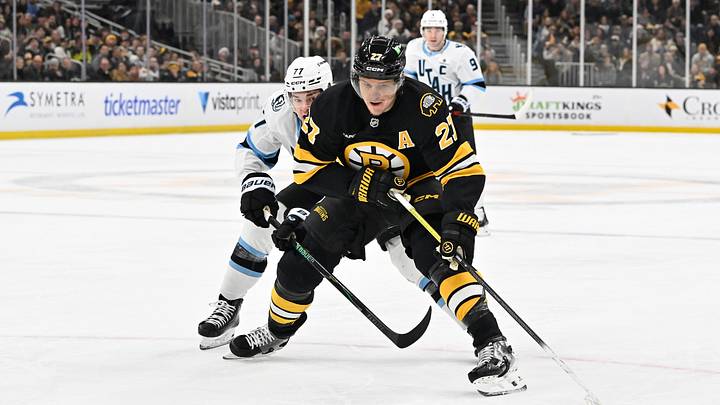 Dec 16, 2025; Boston, Massachusetts, USA; Utah Mammoth right wing JJ Peterka (77) tries to check the shot by Boston Bruins defenseman Hampus Lindholm (27) during the first period at TD Garden. Mandatory Credit: Eric Canha-Imagn Images