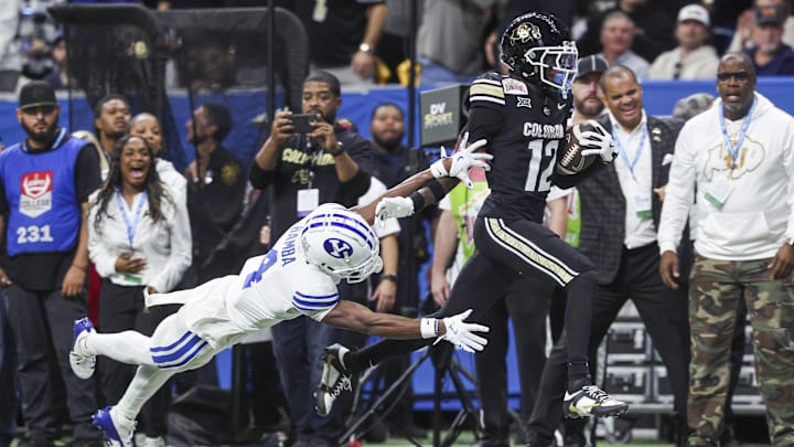 Dec 28, 2024; San Antonio, TX, USA; Colorado Buffaloes wide receiver Travis Hunter (12) runs with the ball as Brigham Young Cougars cornerback Mory Bamba (4) attempts to make a tackle during the second quarter at Alamodome. Mandatory Credit: Troy Taormina-Imagn Images