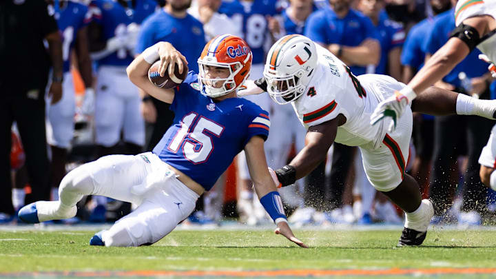Aug 31, 2024; Gainesville, Florida, USA; Florida Gators quarterback Graham Mertz (15) slides for a first down while Miami Hurricanes defensive lineman Rueben Bain Jr. (4) attempts to tackle during the first half at Ben Hill Griffin Stadium. Mandatory Credit: Matt Pendleton-Imagn Images