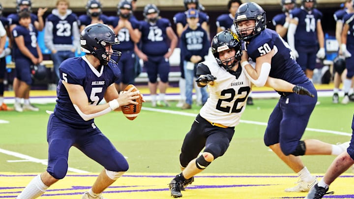 Bedford senior quarterback Conner Nally (5) is forced to rush his pass as the Bishop Garrigan (Algona) Golden Bears compete against the Bedford Bulldogs for the Eight-Player championship on Thursday, November 16, 2023 at the UNI-Dome in Cedar Falls. Bedford senior quarterback Conner Nally (5) is forced to rush his pass as the Bishop Garrigan (Algona) Golden Bears compete against the Bedford Bulldogs for the Eight-Player championship on Thursday, November 16, 2023 at the UNI-Dome in Cedar Falls.