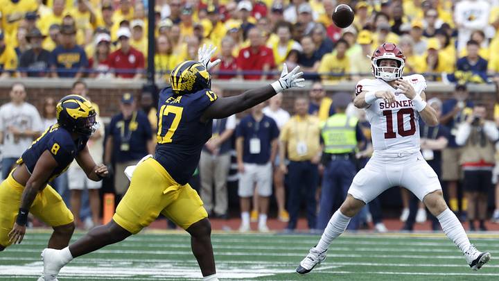 Oklahoma Sooners quarterback John Mateer passes the ball under pressure from Michigan Wolverines defensive line Enow Etta Oklahoma Sooners quarterback John Mateer passes the ball under pressure from Michigan Wolverines defensive line Enow Etta