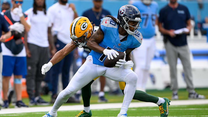 Sep 22, 2024; Nashville, Tennessee, USA;  Green Bay Packers cornerback Eric Stokes (21) tackles Tennessee Titans wide receiver DeAndre Hopkins (10) after a made catch during the first half at Nissan Stadium.
