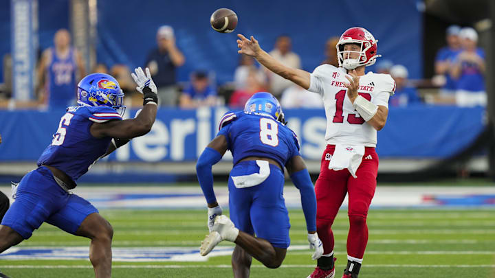 Aug 23, 2025; Lawrence, Kansas, USA; Fresno State Bulldogs quarterback E.J. Warner (13) throws a pass against Kansas Jayhawks defensive end Justice Finkley (15) and linebacker Jon Jon Kamara (8) during the first half at David Booth Kansas Memorial Stadium. Mandatory Credit: Jay Biggerstaff-Imagn Images