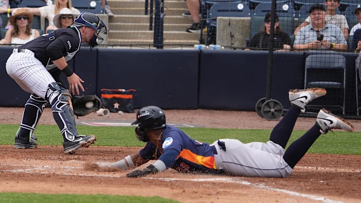 Mar 1, 2025; Tampa, Florida, USA; Houston Astros first baseman Luis Castro (92) slides safely into home against New York Yankees catcher Ben Rice (93) during the third inning at George M. Steinbrenner Field. 