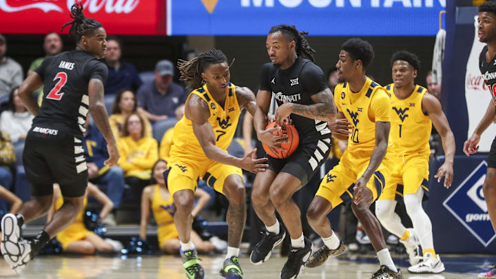 Feb 19, 2025; Morgantown, West Virginia, USA; West Virginia Mountaineers guard Javon Small (7) and Cincinnati Bearcats guard Day Day Thomas (1) fight for a loose ball during the second half at WVU Coliseum. Mandatory Credit: Ben Queen-Imagn Images