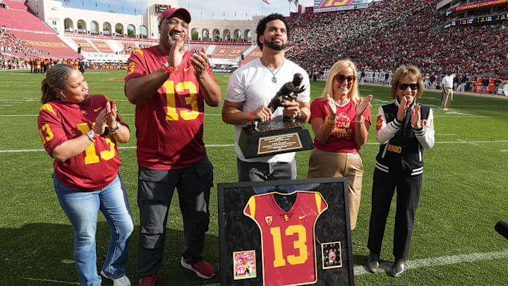 Nov 30, 2024; Los Angeles, California, USA; Chicago Bears and former Southern California Trojans quarterback Caleb Williams (center) holds Heisman Trophy and poses (from left) mother Dayne Price, father Carl Williams, athletic director Jennifer Cohen and president Carol Folt during jersey retirement ceremony at United Airlines Field at Los Angeles Memorial Coliseum. Mandatory Credit: Kirby Lee-Imagn Images