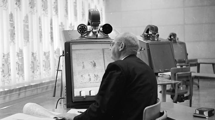 Man reading from a microfilm machine, which uses a similar technology to Brown's "Readies."