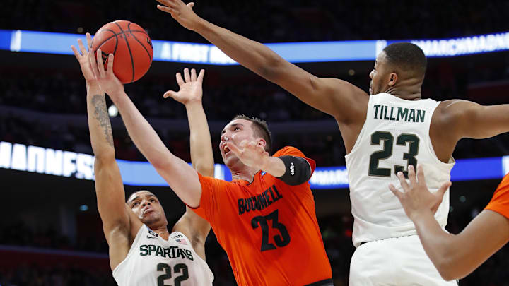 Mar 16, 2018; Detroit, MI, USA; Bucknell Bison forward Zach Thomas (23) goes to the net defended by Michigan State Spartans guard Miles Bridges (22) and forward Xavier Tillman (23) in the first half in the first round of the 2018 NCAA Tournament at Little Caesars Arena. Mandatory Credit: Rick Osentoski-Imagn Images