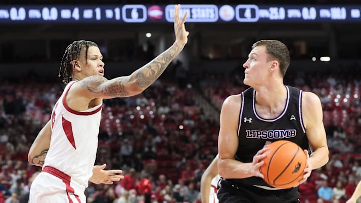 Jacob Ognacevic, now with the UW, looks for an opening for Lipscomb against Arkansas forward Trevon Brazile last November.