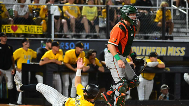 Southern Miss Golden Eagles infielder Nick Monistere (8) slides into home behind Miami Hurricanes catcher Tanner Smith (30) during the final game of the 2025 NCAA Hattiesburg Regional game at Pete Taylor Park in Hattiesburg, Mississippi, on June 2, 2025.