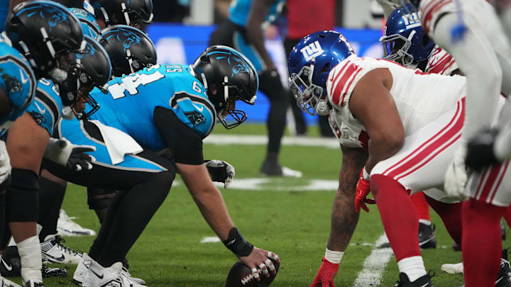 Nov 10, 2024; Munich, Germany; Helmets at the line of scrimmage as Carolina Panthers guard Cade Mays (64) snaps the ball against the New York Giants in the first half during the 2024 NFL Munich Game at Allianz Arena. 