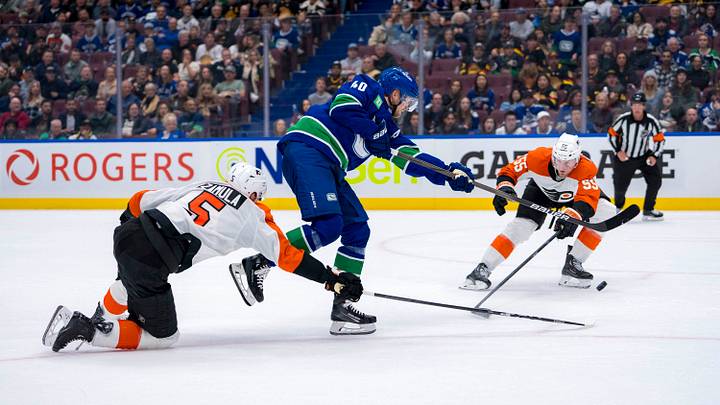Oct 11, 2024; Vancouver, British Columbia, CAN; Philadelphia Flyers defenseman Egor Zamula (5) and defenseman Rasmus Ristolainen (55) stick check Vancouver Canucks forward Elias Pettersson (40) during the third period at Rogers Arena. Mandatory Credit: Bob Frid-Imagn Images