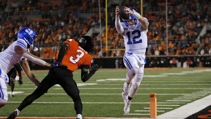 Nov 25, 2023; Stillwater, Oklahoma, USA; BYU's Jake Retzlaff (12) scores a touchdown against Oklahoma State's Cam Smith (3) in the first overt time   at Boone Pickens Stadium. Mandatory Credit: Sarah Phipps-Imagn Images