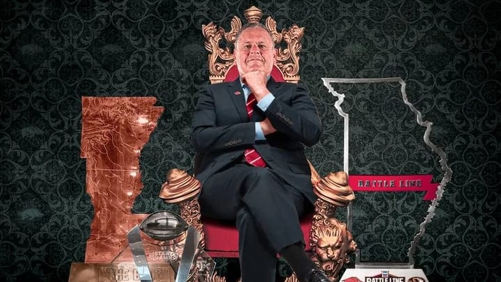 Arkansas coach Sam Pittman sits on a throne surrounded by trophies collected by his team throughout the 2021 season.