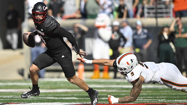 Oct 19, 2024; Louisville, Kentucky, USA;   Louisville Cardinals quarterback Tyler Shough (9) looks to pass under the pressure of Miami Hurricanes defensive lineman Tyler Baron (9) during the second half at L&N Federal Credit Union Stadium. Miami defeated Louisville 52-45. Mandatory Credit: Jamie Rhodes-Imagn Images