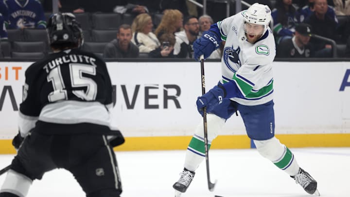 Feb 26, 2025; Los Angeles, California, USA; Vancouver Canucks defenseman Carson Soucy (7) shoots against Los Angeles Kings center Alex Turcotte (15) during the first period at Crypto.com Arena. Mandatory Credit: Jason Parkhurst-Imagn Images