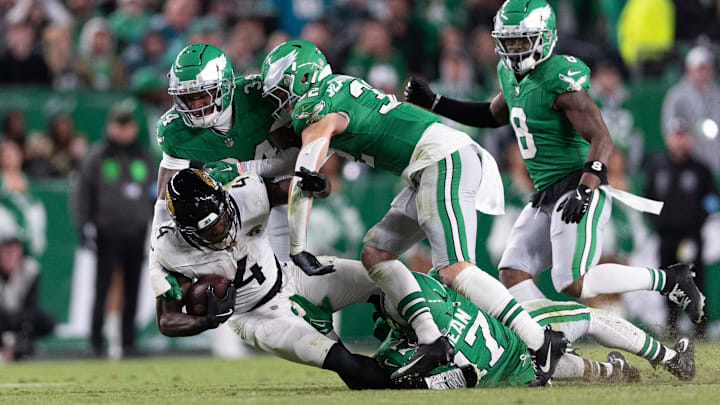 Nov 3, 2024; Philadelphia, Pennsylvania, USA; Jacksonville Jaguars running back Tank Bigsby (4) is tackled by Philadelphia Eagles linebacker Nakobe Dean (17) and cornerback Isaiah Rodgers (34) during the fourth quarter at Lincoln Financial Field. Mandatory Credit: Bill Streicher-Imagn Images